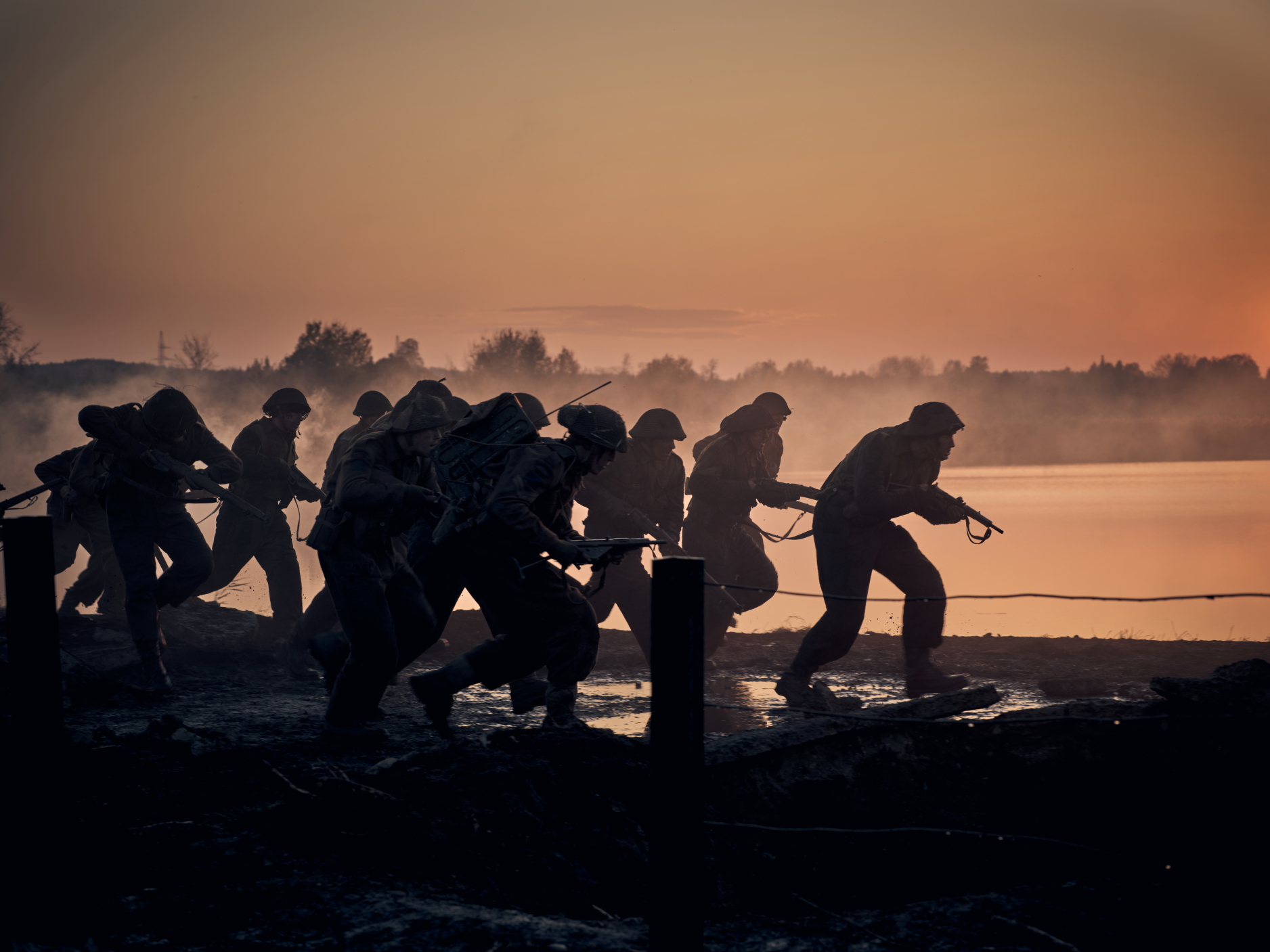 Soldiers move stealthily on the edge of a river.